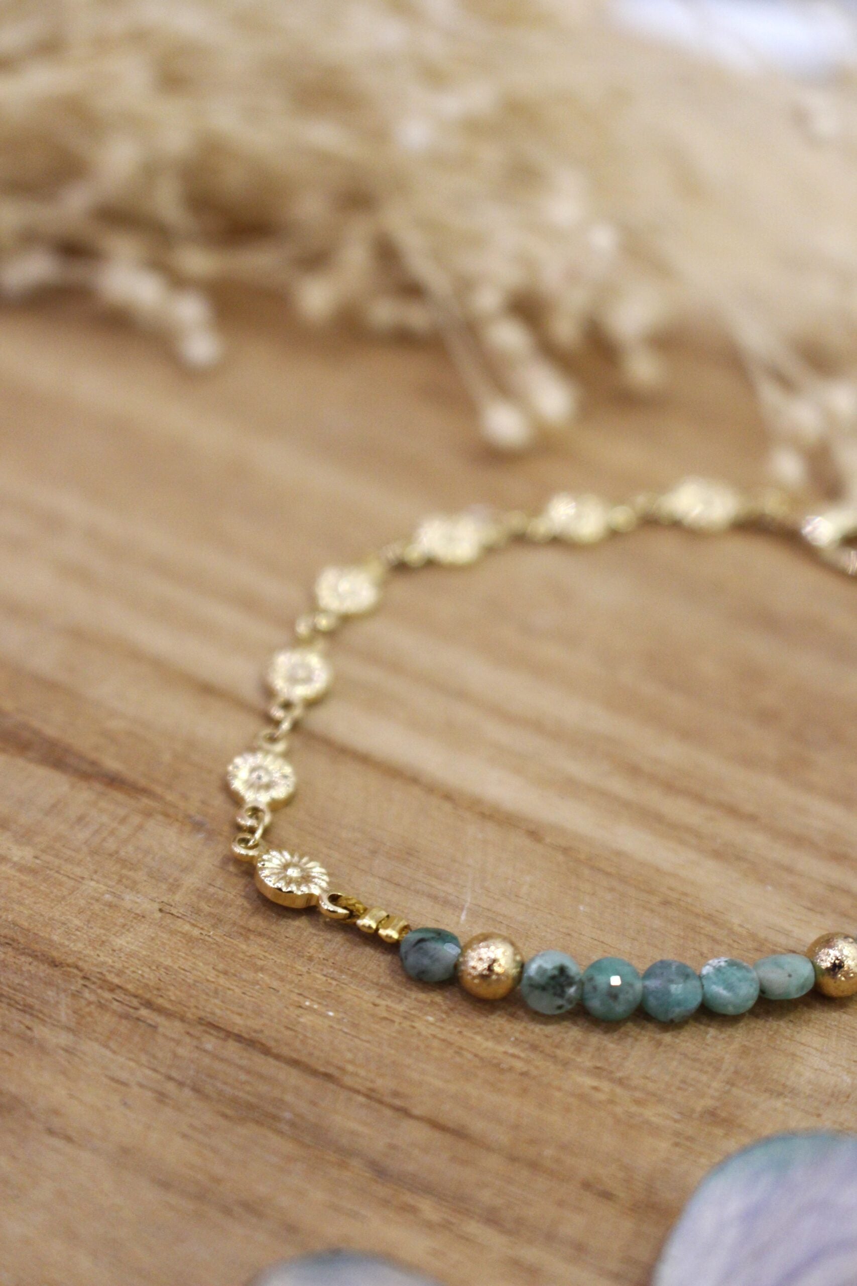 bracelet orné de petites fleurs dorées et de perles émeraude brut