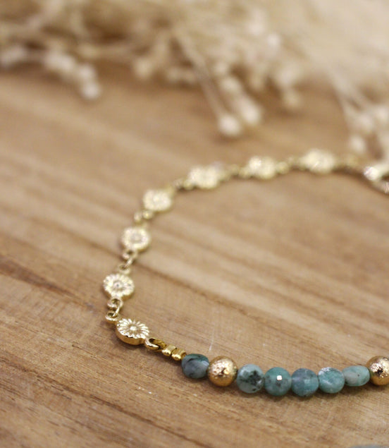 bracelet orné de petites fleurs dorées et de perles émeraude brut