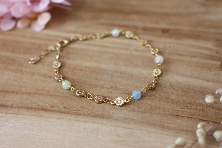bracelet pour femme, collection printemps, composé d'une chaîne en fleurs dorées et orné de perle en aigue marine