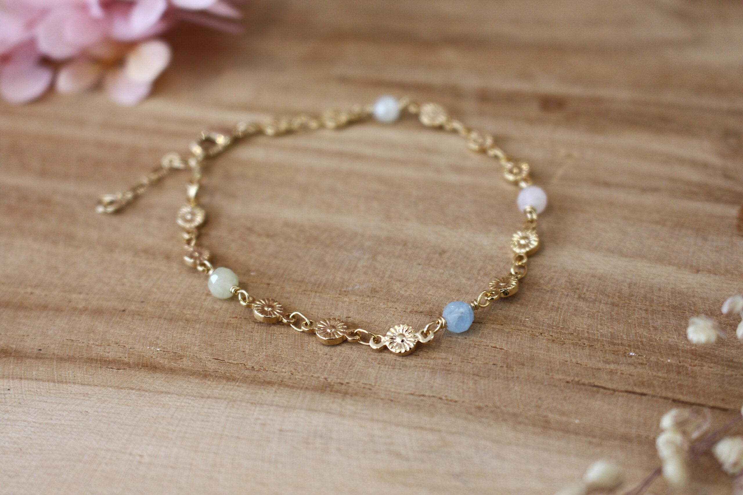 bracelet pour femme, collection printemps, composé d'une chaîne en fleurs dorées et orné de perle en aigue marine