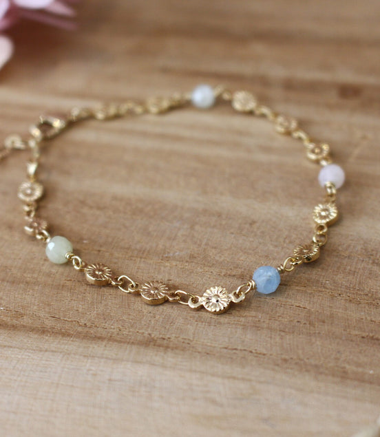 bracelet pour femme, collection printemps, composé d'une chaîne en fleurs dorées et orné de perle en aigue marine