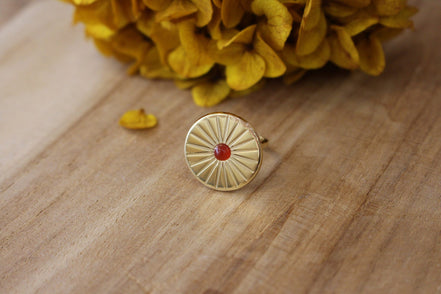 bague doré en forme de soleil avec un cabochon en cornaline