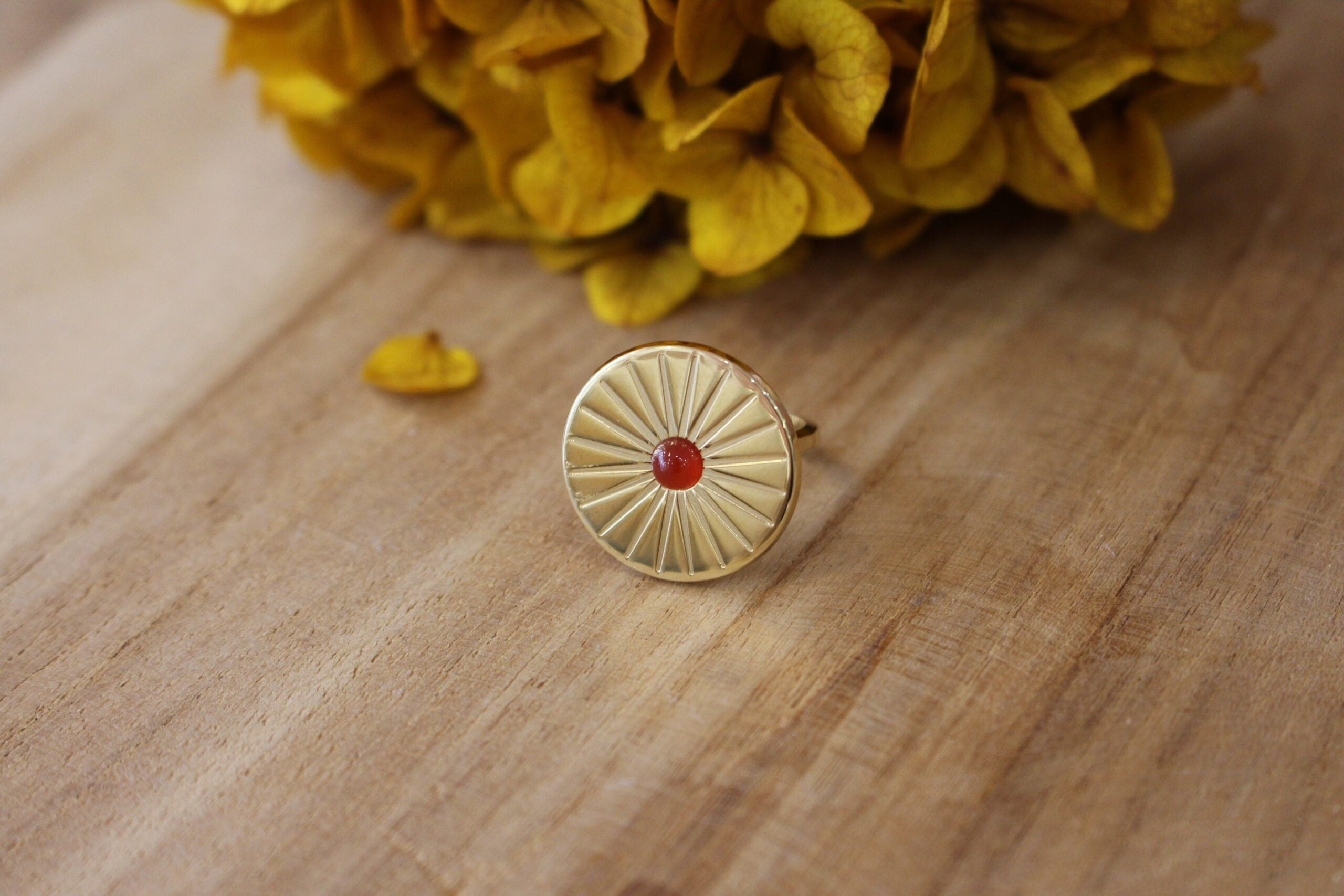 bague doré en forme de soleil avec un cabochon en cornaline