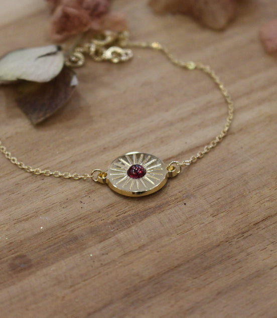 bracelet gourmette et médaille soleil plaqué or orné d'un grenat